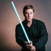 Artist Charles Ross holding blue lightsaber.